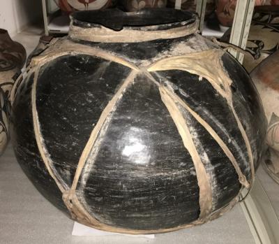 Blackware storage jar with rawhide strapping. Santa Clara Pueblo, Rawhide strapping has torn and is detaching from the jar, Photo courtesy of the Museum of Indian Arts & Culture