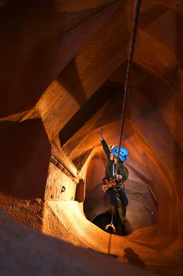Merrick waves through a window from the vertical cave to the childrens playroom in CaveSim at CityROCK Climbing Gym. Photo by Mark Reis, The Colorado Gazette.