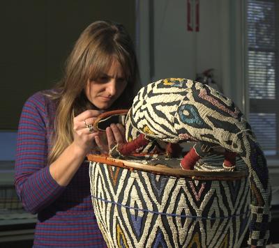Conservator Sophie Hunter repairs bead work on a ceremonial mask for Beadwork