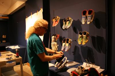 Preparator Paul Singdahlsen installs beaded moccasins in Stepping Out.